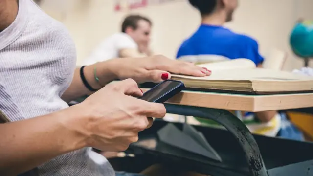 Estudante ao celular na salaeurowin double xaula