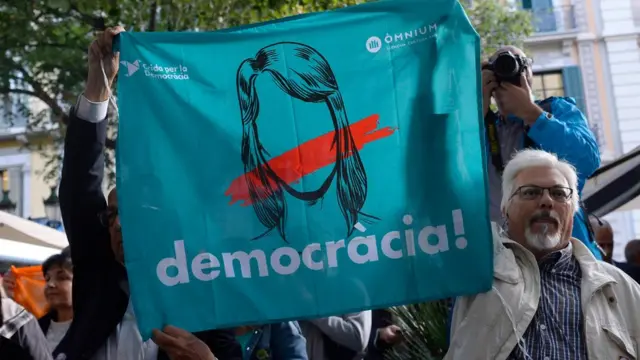 Protestantes con carteles que dicen: Democracia.