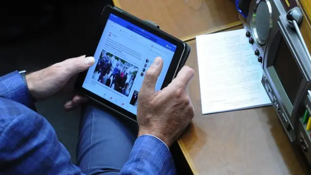 Народний депутат України переглядає на планшеті новинну стрічку у соціальній мережі