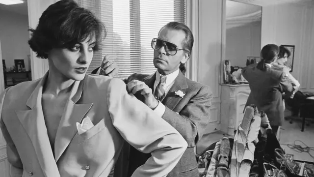 Lagerfeld as im dey fit one of im designs on top model Ines de la Fressange for Chloe Paris studio.