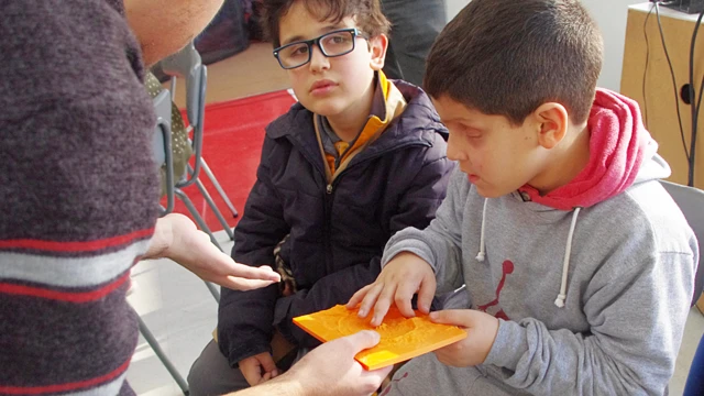 Niños tocando una maqueta que representa un cráter