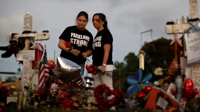 Heather Mesch (C) and her daughter Alexa place roses next to crosses placed in front of the fence of the Marjory Stoneman Douglas High School to commemorate the victims of the mass shooting, in Parkland, Florida, U.S., February 21, 2018
