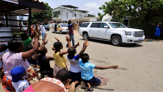 Children raise their arms as Eric Norbert Abekan travels past in Abidjan, Ivory Coast - Sunday 20 March 2020