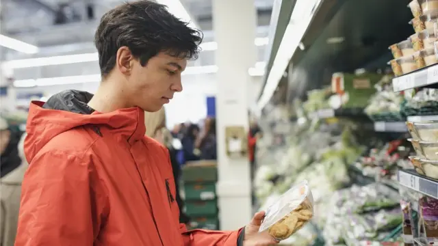 Joven eligiendo un producto en el supermercado.