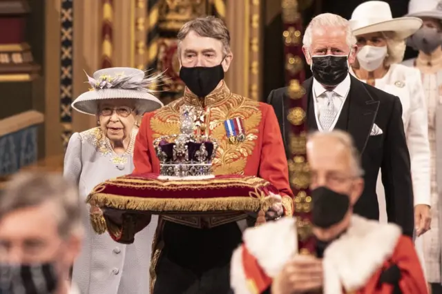 Queen Elizabeth II, accompanied by the Prince of Wales, proceeds through the Royal Gallery before delivering the Queen"s Speech during the State Opening of Parliament in the House of Lords at the Palace of Westminster in London