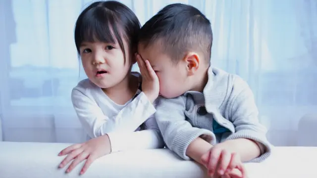 A little girl and her small brother. They like and dislike each other.