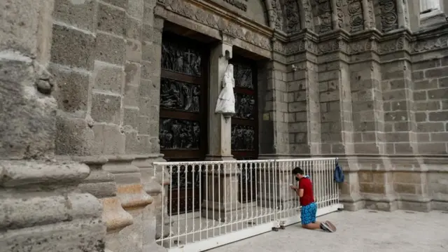 A man prays in front of a closed cathedral in Manila, Philippines