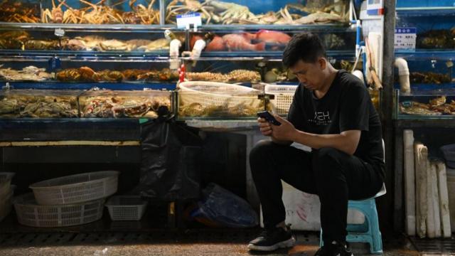 北京某水产市场内一名摊主在等待顾客光顾（24/8/2023）