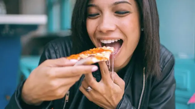 perempuan makan pizza