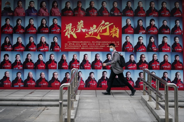 上海一名男子走过致敬武汉医护人员的宣传海报。