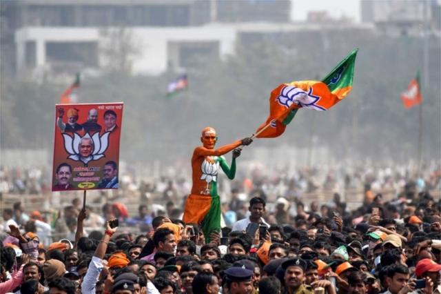 An Indian Bharatiya Janata Party (BJP) supporter waves a flag among the crowd of other supporters listening to Prime Minister Narendra Modi during the National Democratic Alliance (NDA) "Sankalp" rally in Patna in the Indian eastern state of Bihar on March 3, 2019