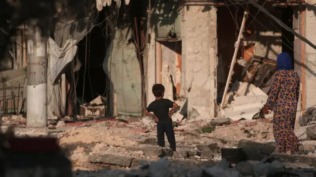 Мальчик и денщина среди руин в Алеппо