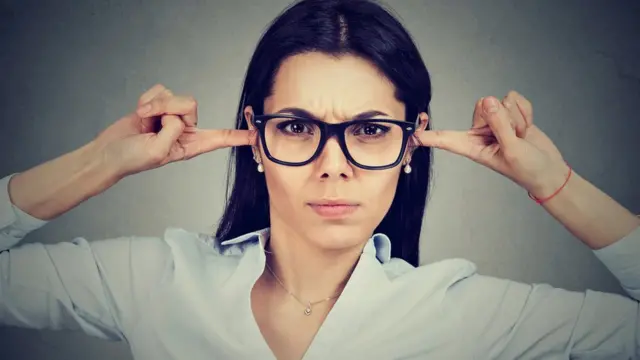 Une femme se bouche les oreilles