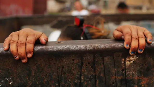 Manos de una niña sobre un cerco en América Latina