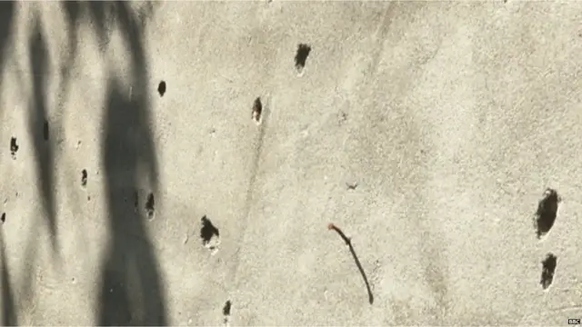 ਦਫ਼ਤਰ ਦੀ ਇੱਕ ਕੰਧ 'ਤੇ ਗ੍ਰੇਨੇਡ ਹਮਲੇ ਨਾਲ ਹੋਈਆਂ ਮੋਰੀਆਂ ਅਤੇ ਧਾਤੂ ਨਾਲ ਬਣੇ ਕਈ ਖੱਡੇ ਹਨ