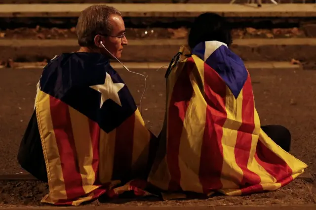 Dos personas siguen por radio la comparecencia de Carles Puigdemont el 10 de octubre de 2017