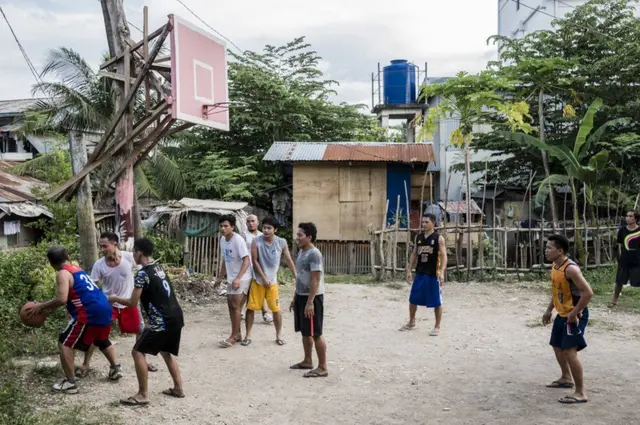 شباب يلعبون السلة، بعضهم يرتدي ملابس رياضية