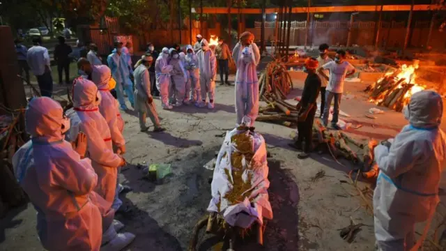 দিল্লির একটি শ্মশানে মৃত স্বজনকে চিতায় তুলছেন পিপিই পরা আত্মীয়-পরিজন