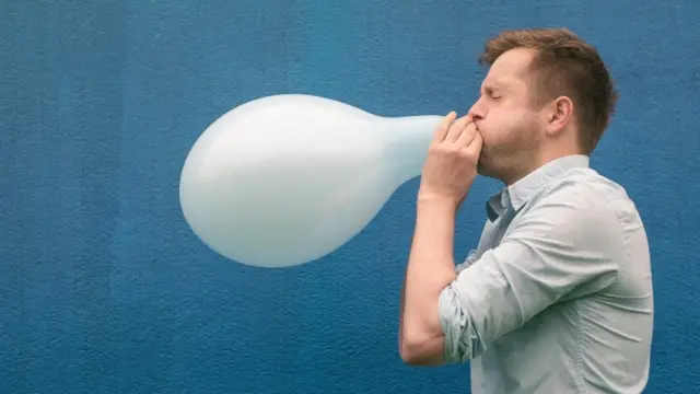 Homem enchendo um balão