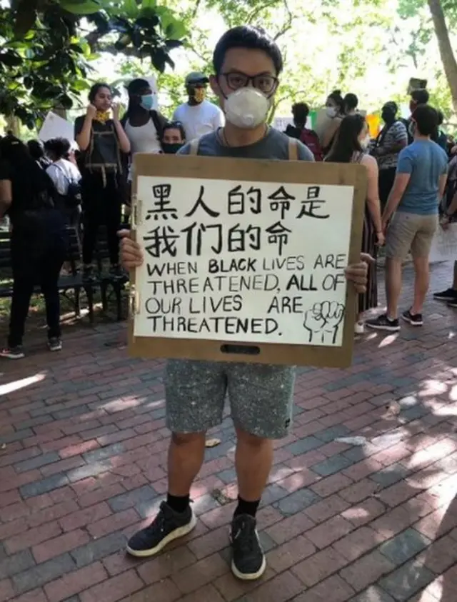 一名亞裔示威者舉著"黑人的命是我們的命"的中英文標語。