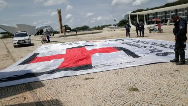 Policial observando bandeira com símbolonazista com imagem de Bolsonaro