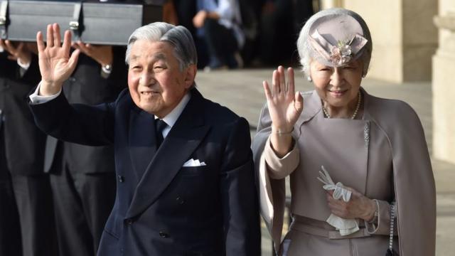 The then Emperor Akihito (L) and Empress Michiko (R) wave to well-wishers