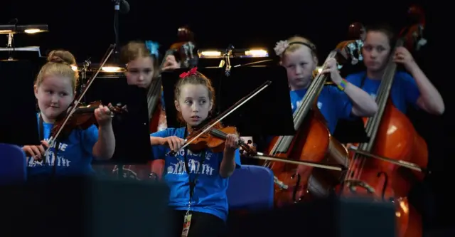 Niñas tocando sus instrumentos musicales durante un concierto