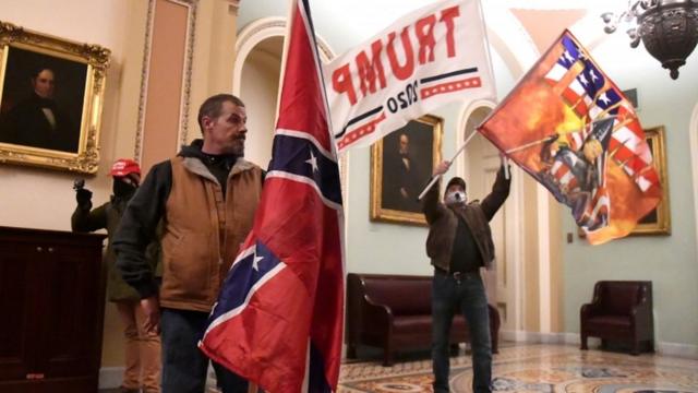 議事堂内でトランプ氏支持の旗を掲げる侵入者たち