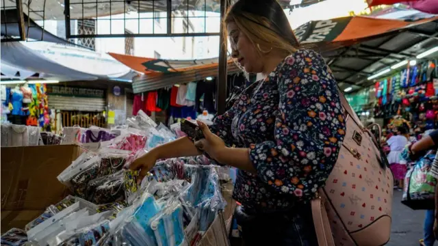 Una mujer compra mascarillas en un puesto de un mercado