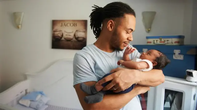 Pai com dreadlocks presos num rabojogos para jogar com amigos online pccavalo acalentando um bebê