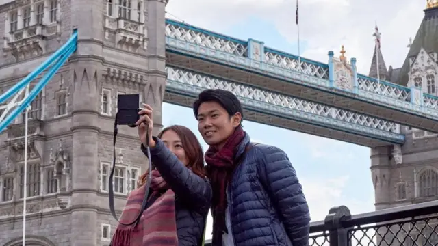 Casal jovem tira fotoestrategia futebol virtual betanofrente à Tower Bridge,estrategia futebol virtual betanoLondres