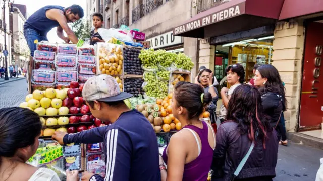 Un camión con frutas ofrece sus productos a los transeúntes.