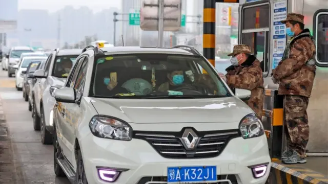 A militia member checks the body temperature of a passenger on a vehicle at an expressway toll gate in Wuhan, central China"s Hubei province, 23 January 2020.