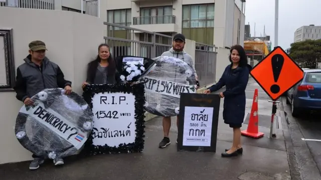 ธนบดี ญาติสังกัด (3 จากซ้าย) และเพื่อนคนไทยในนิวซีแลนด์เดินทางมาวางพวงหรีดเพื่อแสดงความไว้อาลัยและประท้วงต่อความไม่ยุติธรรม หลังบัตรเลือกตั้งโดยคนไทยในนิวซีแลนด์ 1,542 ใบถูกทำให้เป็นบัตรเสีย