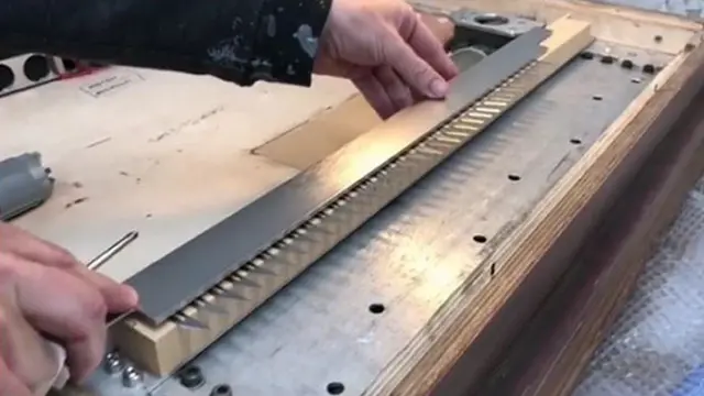 Banksy instalando la trituradora de papel en el marco de la obra.