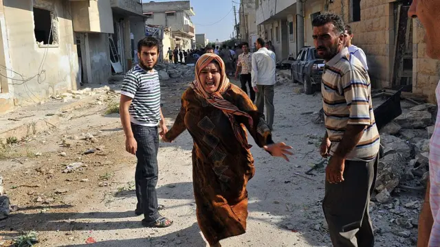 سيدة سورية تركض بين الأنقاض بعد غارة جوية على بلدة اعزاز ، بالقرب من مدينة حلب شمال سوريا في 15 أغسطس / آب 2012