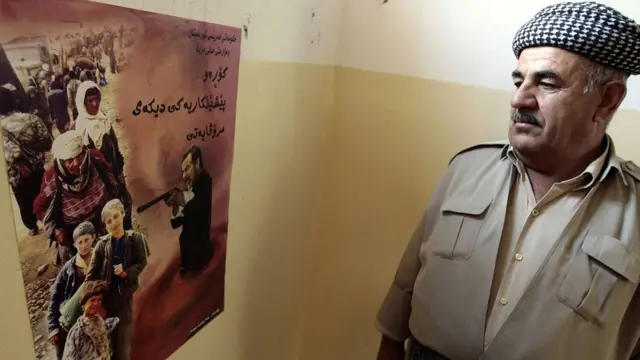 یک شاهد که از عملیات انفال جان سالم به در برده بود، به پوستر اولین روز محاکمه صدام درباره این کشتار خیره شده است