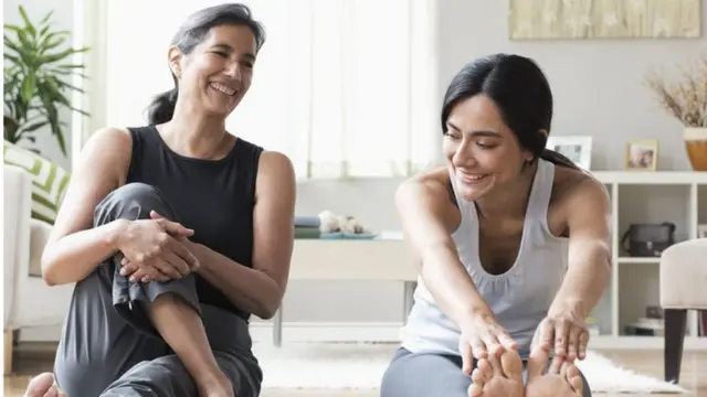 Dos mujeres realizan estiramientos en la sala de una casa