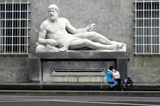 A sculpture and couple kissing