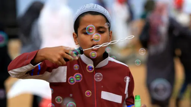 ঈদের দিনে একটি ছেলে বুদবুদ উড়িয়ে আনন্দ করছে।