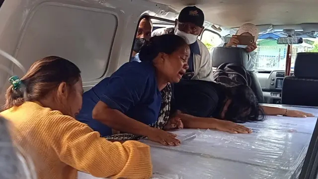 Seorang perempuan menangis di depan jenazah keluarganya yang tewas saat menjadi PMI di Malaysia.