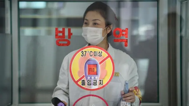 2021년 10월 20일 평양역전백화점 직원이 체온 측정과 손 소독을 위해 손님을 기다리고 있다