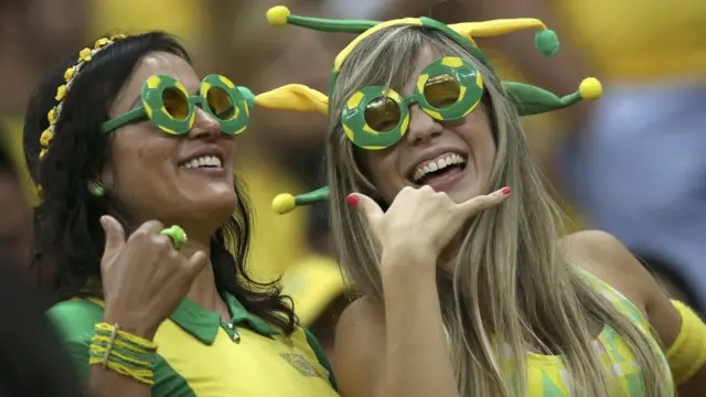 Dos seguidoras de la selección brasilera sonríen a las cámaras.