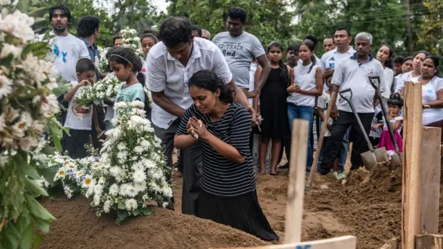 Mulher chorandocriar conta pixbetfrente ao túmulocriar conta pixbetuma das vítimas