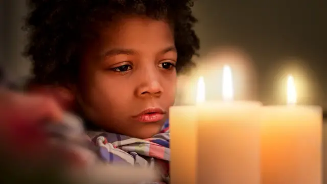 Niño mirando las llamas de velas