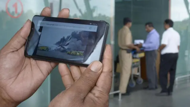 கடந்த ஆண்டு துபாயில் நடைபெற்ற விமான விபத்தில் விமானம் தீப்பற்றி எரியும்போதும் பயணிகள் தங்கள் உடமைகளை எடுப்பதற்காக நிற்கிறார்கள்