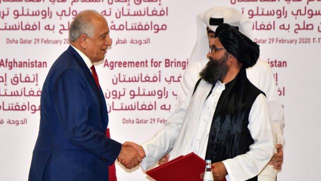 US Special Representative for Afghanistan Reconciliation Zalmay Khalilzad and Taliban co-founder Mullah Abdul Ghani Baradar shake hands after signing a peace agreement