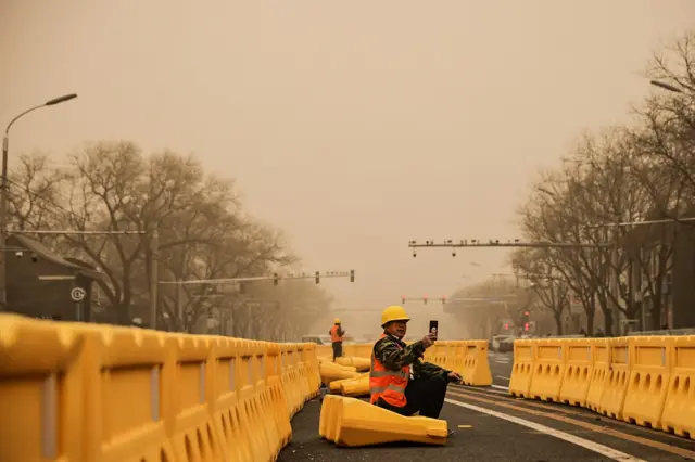 一名道路工作者用手機拍照。
