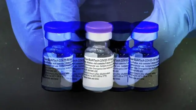 มือคนจับขวดวัคซีน