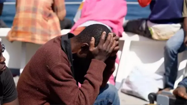 Un migrant se prend la tête entre les mains, signe de désespoir.